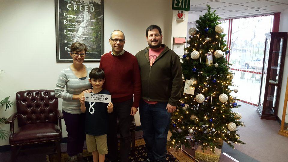 deacon Jim with a family in front of Christmas tree
