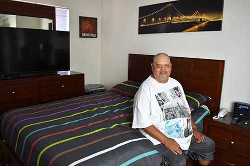 Senior Living Homeless in San Diego | Sebastian sits on the edge of his bed in his new apartment.