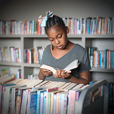 Tutoring Programs | A little girl reads in the Therapeutic Childcare library.