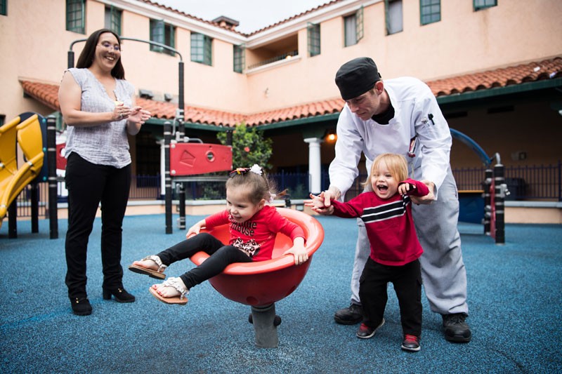 Nina and Stephen play with their kids on the playground. | homeless family help