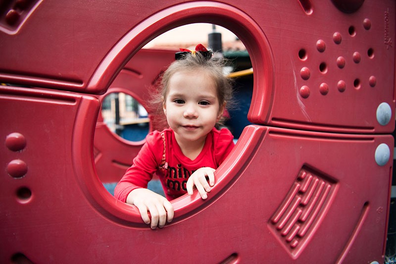 Child peeks through a playground structure. | homeless family help