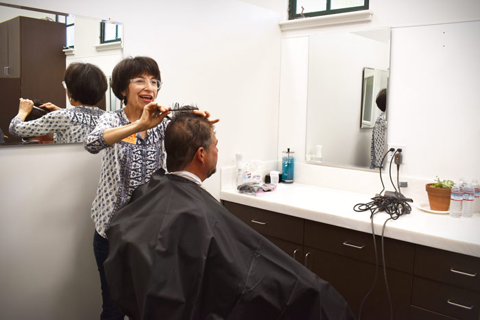 Volunteer hairdresser cuts a client's hair before his interview. | haircuts for homeless